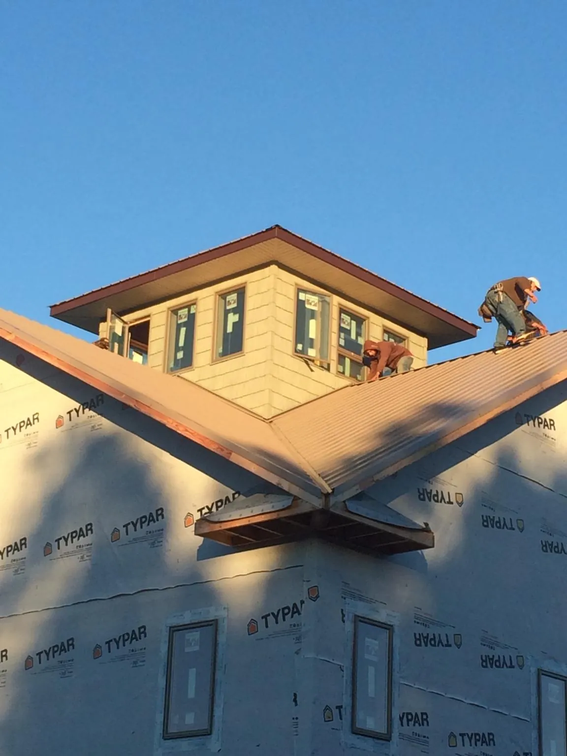 Roofers working around a rooftop cupola on a new metal roof at sunset — Roof Waterproofing in Pikeville by Roofing Brothers